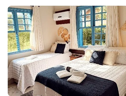 Quarto com duas camas, janelas azuis e roupa de cama branca